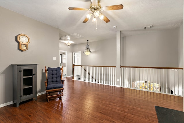 living area with wood finished floors, a ceiling fan, visible vents, attic access, and a textured ceiling