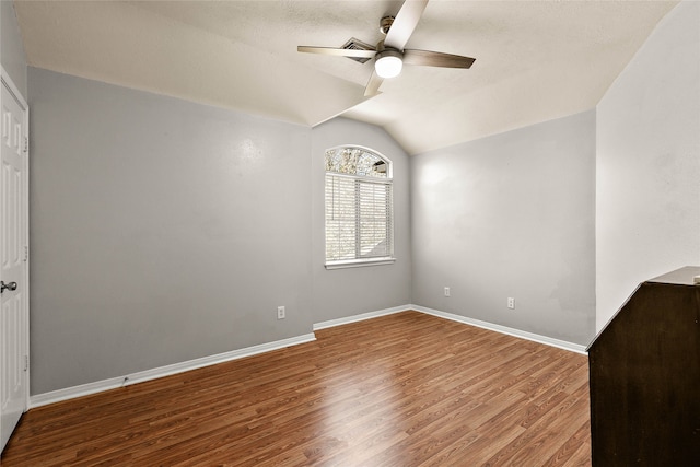 unfurnished room with baseboards, lofted ceiling, ceiling fan, and wood finished floors