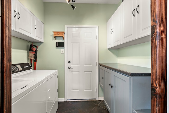 washroom with dark tile patterned floors, baseboards, cabinet space, and washing machine and dryer