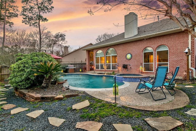 view of pool featuring a patio, a pool with connected hot tub, and fence