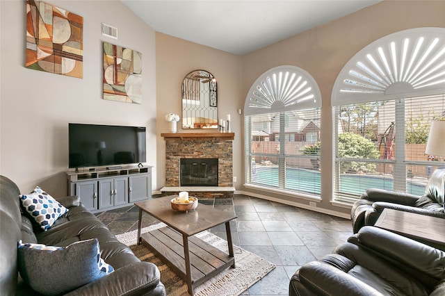 living room with visible vents, lofted ceiling, a stone fireplace, and stone tile flooring