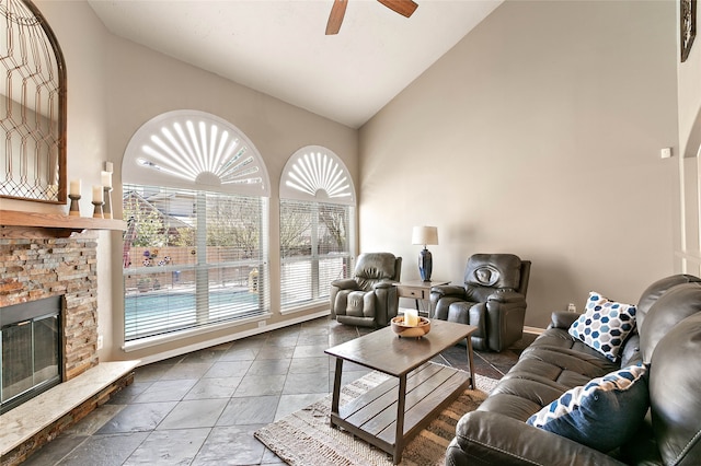 living room featuring a fireplace, high vaulted ceiling, and a ceiling fan