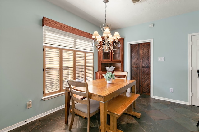 dining space featuring an inviting chandelier, baseboards, and stone tile flooring