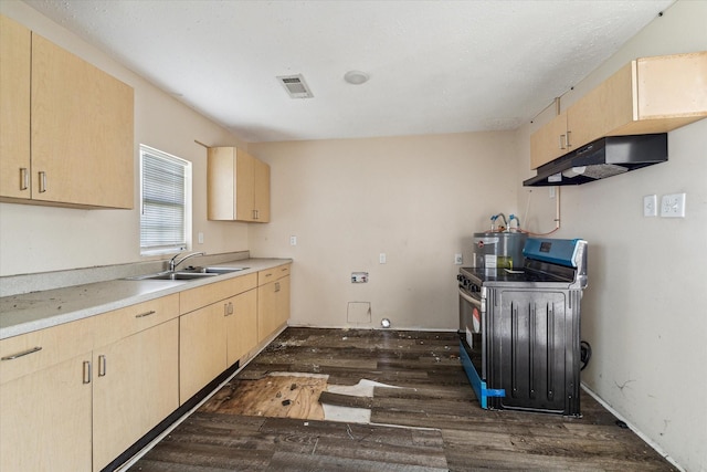 kitchen with dark wood-type flooring, light brown cabinetry, stainless steel range with electric cooktop, light countertops, and washer / dryer