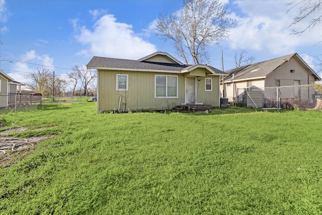 rear view of house with a lawn and fence