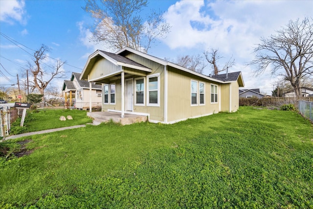 back of house with a patio, roof with shingles, a yard, and fence