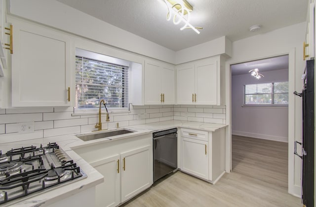 kitchen with stainless steel gas cooktop, a sink, white cabinets, black dishwasher, and a chandelier