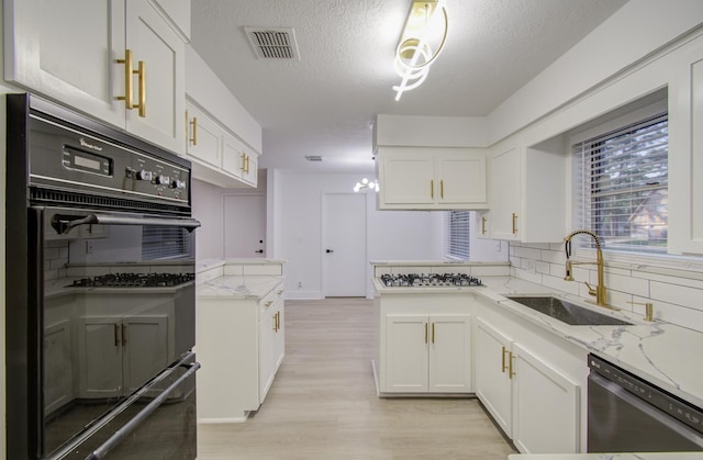 kitchen with a sink, white cabinets, visible vents, and stainless steel appliances