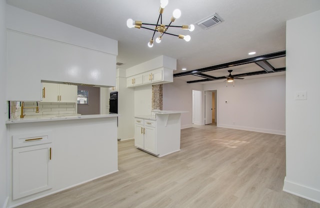 kitchen with black oven, tasteful backsplash, light wood-style floors, a peninsula, and light countertops