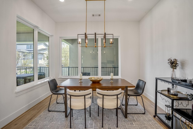 dining area featuring a chandelier, visible vents, baseboards, and wood finished floors