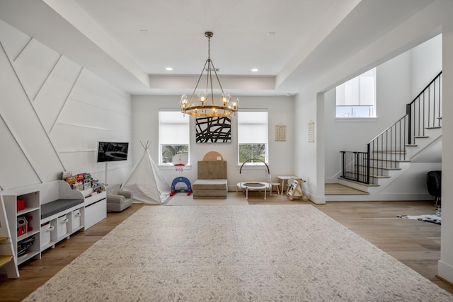 interior space with a chandelier, recessed lighting, a tray ceiling, and wood finished floors