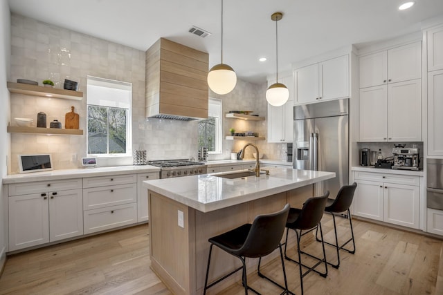 kitchen with open shelves, custom range hood, light wood-type flooring, and a sink