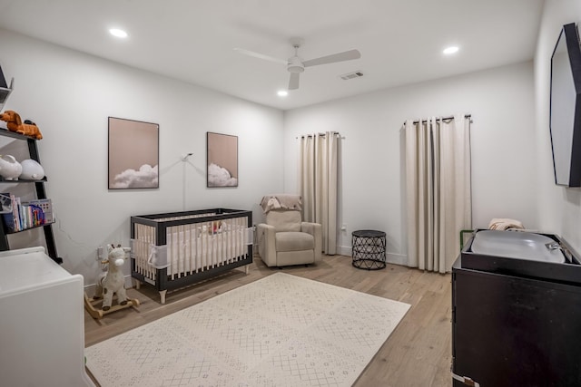 bedroom featuring a nursery area, recessed lighting, visible vents, and light wood-style floors