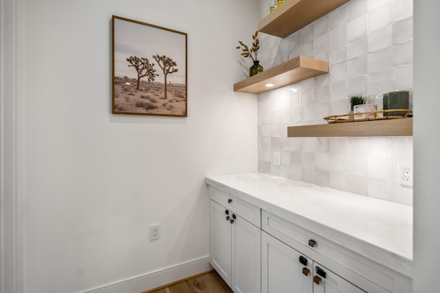 kitchen with open shelves, light countertops, baseboards, and backsplash