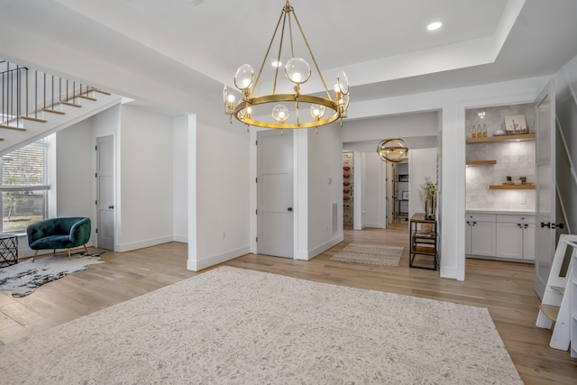 interior space with baseboards, an inviting chandelier, stairs, and light wood finished floors