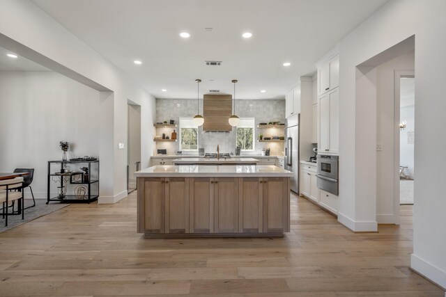 kitchen featuring a warming drawer, open shelves, a kitchen island, stainless steel appliances, and light countertops