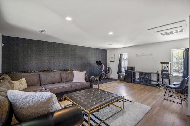 living area featuring an accent wall, recessed lighting, wood finished floors, and visible vents