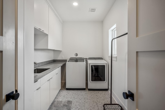 laundry area with baseboards, visible vents, cabinet space, a sink, and washer and clothes dryer