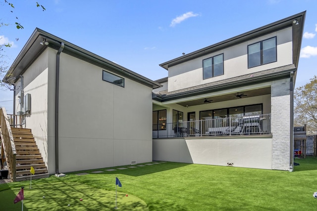 rear view of property with stairway, stucco siding, a ceiling fan, and a yard