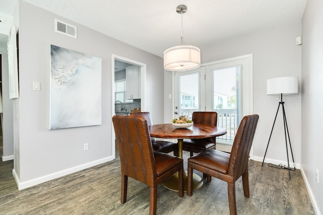 dining area featuring plenty of natural light, baseboards, visible vents, and dark wood-style flooring