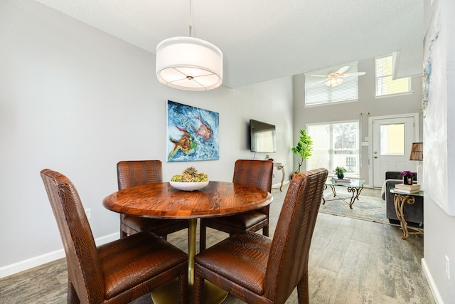 dining space with light wood-type flooring, baseboards, and ceiling fan