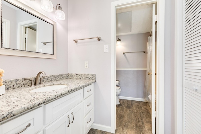 full bathroom with toilet, wood finished floors, a closet, baseboards, and vanity