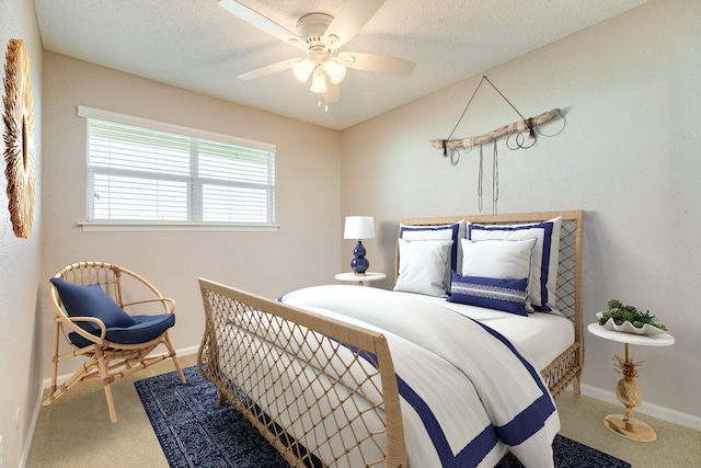 carpeted bedroom with a textured ceiling, baseboards, and a ceiling fan