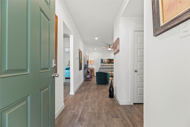 corridor featuring dark wood-type flooring, recessed lighting, and baseboards