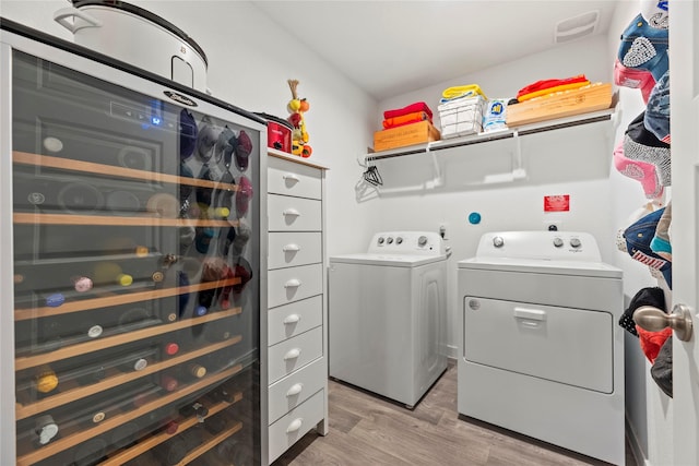 clothes washing area with light wood-type flooring, separate washer and dryer, and laundry area