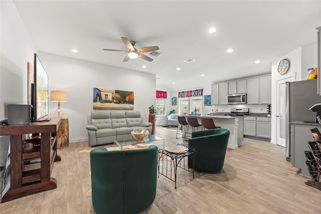 living room featuring recessed lighting, a ceiling fan, visible vents, and light wood-type flooring