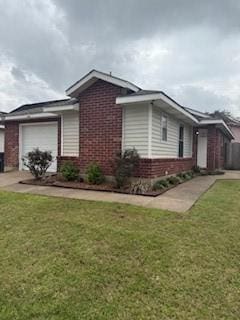 view of side of home featuring brick siding, a lawn, and a garage