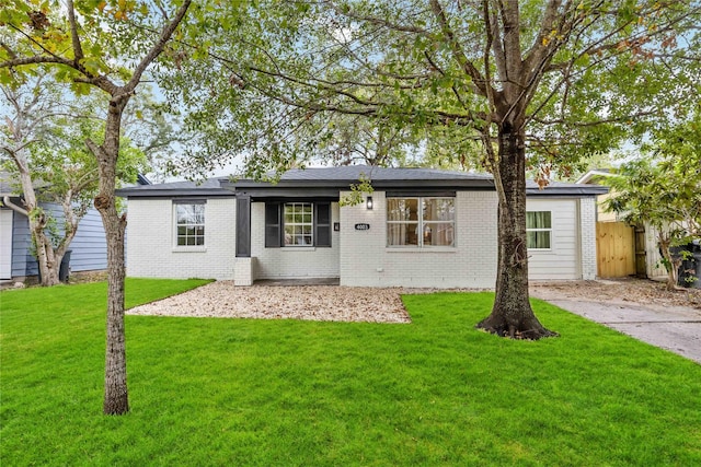 ranch-style home with a front lawn, fence, and brick siding