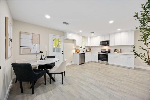 kitchen featuring visible vents, light wood-style floors, appliances with stainless steel finishes, white cabinets, and light countertops