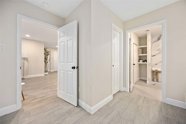 hallway featuring light wood-style flooring and baseboards