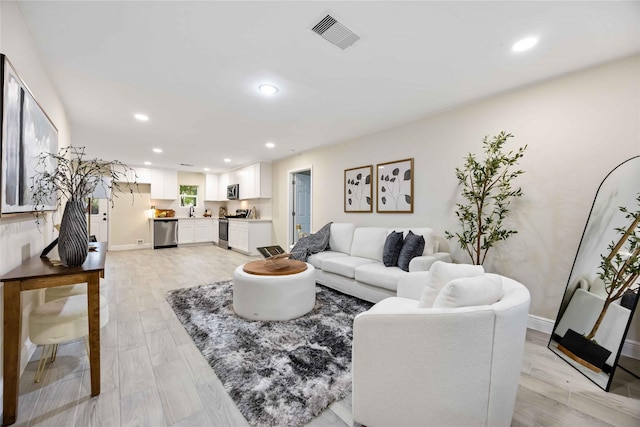 living area featuring baseboards, recessed lighting, visible vents, and light wood-type flooring