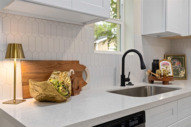 kitchen with backsplash, light stone countertops, white cabinetry, and a sink