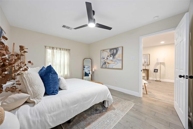 bedroom with light wood-style flooring, visible vents, baseboards, and ceiling fan