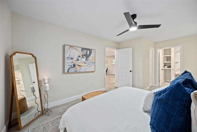 bedroom featuring connected bathroom, baseboards, light wood-style flooring, and a ceiling fan