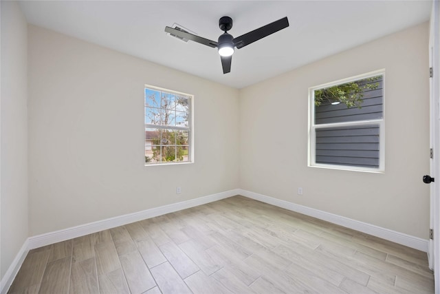 empty room featuring light wood-style floors, a ceiling fan, and baseboards