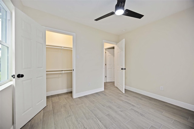 unfurnished bedroom with a closet, baseboards, a ceiling fan, and wood tiled floor