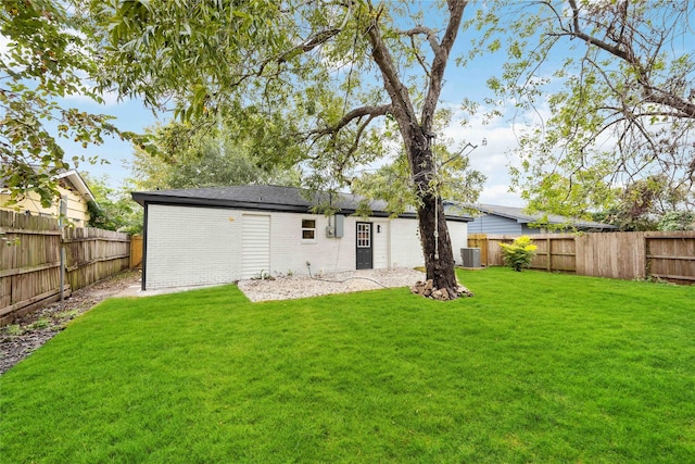 back of property featuring a yard, central AC unit, brick siding, and a fenced backyard