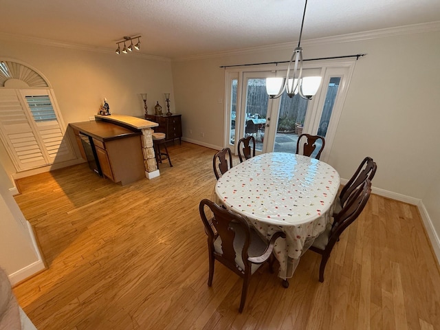 dining room featuring baseboards, ornamental molding, and light wood finished floors