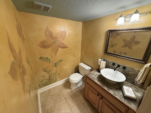 half bathroom featuring vanity, baseboards, visible vents, a textured ceiling, and toilet