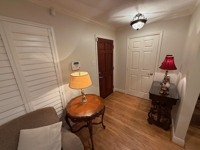 sitting room with light wood-style flooring, crown molding, and baseboards