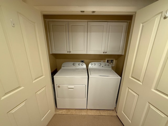 washroom with light tile patterned flooring, washing machine and dryer, and cabinet space