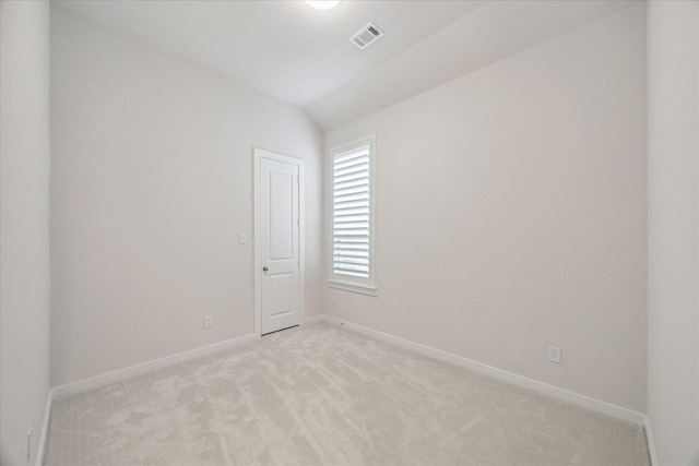 unfurnished room with visible vents, light colored carpet, baseboards, and vaulted ceiling