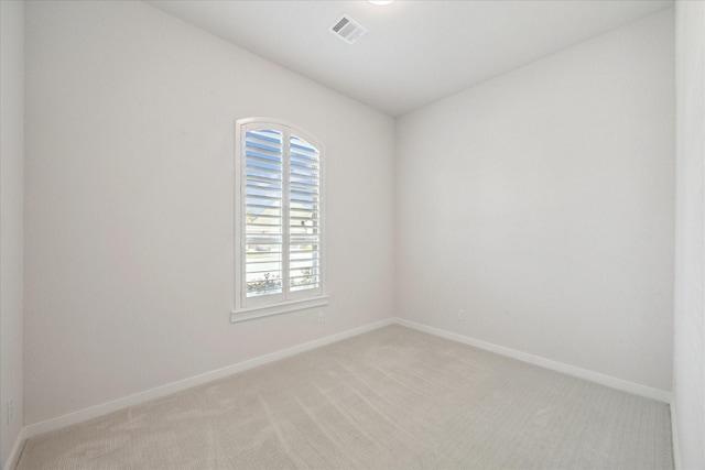 unfurnished room featuring visible vents, light carpet, and baseboards