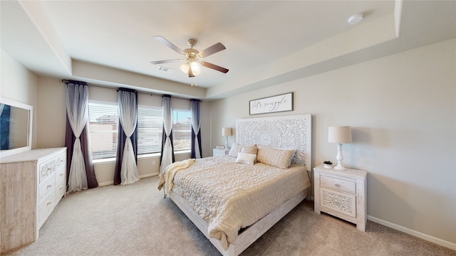 bedroom featuring a tray ceiling, visible vents, baseboards, and light colored carpet