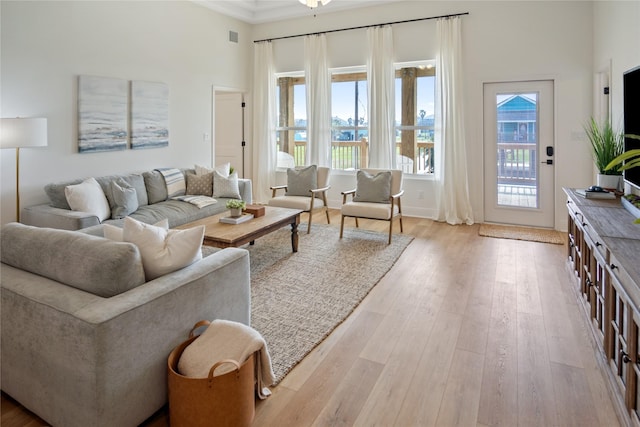 living area with wood finished floors, visible vents, and a towering ceiling