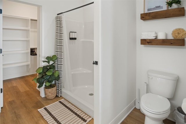 full bath with a stall shower, toilet, and wood finished floors